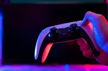 Modern gamepad in a gamer's hand on a dark background. Minimalism. Video games with friends,...