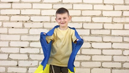 smiling adorable Ukrainian boy is happy with the victory of his country. children against war. fan patriot with big Ukrainian flag in hands. emotional face successful person - Powered by Adobe