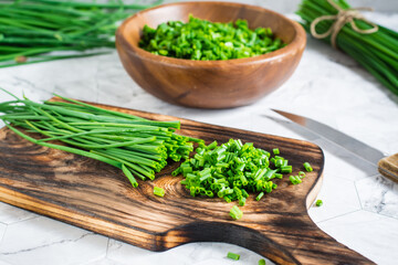 Obraz na płótnie Canvas Sliced fresh green onions on a cutting board on the table. Spring vitamin harvest. Close-up