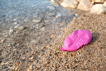 Fototapeta na wymiar Plastic bottle pink on the seashore. Beach pollution.