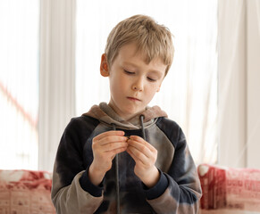 a boy in a bright room at a table enthusiastically collects a constructor