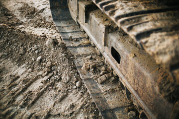 Metal excavator track background. Construction site sandy ground. House building background. Heavy machinery equipment.