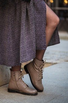 Close up legs of woman wearing stylish dress and leather shoes with tyed laces stands in the street