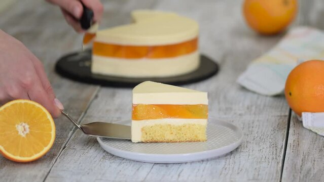 Piece of orange mousse cake with jelly and orange slices.