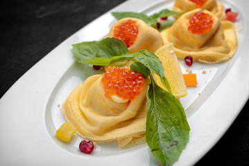 Pancakes with red caviar, basil, dark background