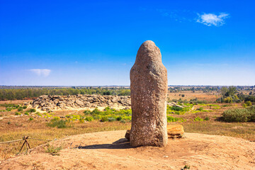 View of the ancient kurgan stela, stone idol against the backdrop of Kamyana Mohylain is an archaeological site in the Molochna River, Zaporizhzhia Oblast, Ukraine - obrazy, fototapety, plakaty