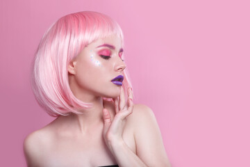 attractive young woman with pink bob cut and purple lips looking at camera isolated on pink...