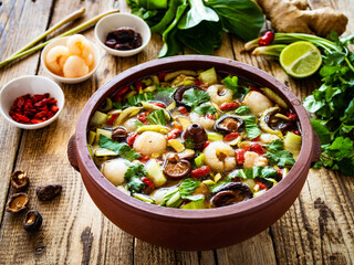 Yunnan hot pot - chinese soup with chicken meat on wooden table

