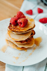 Pancakes with raspberries lying on the table, stacking