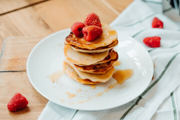 Pancakes with raspberries lying on the table, stacking