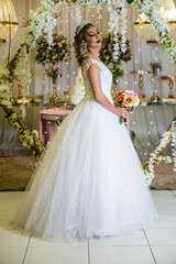 Fototapeta premium young caucasian brazilian bride at her wedding with decorated background, makeup and hairstyle.