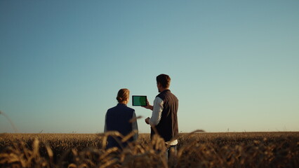 Farmers using pad computer for online communication with partners at wheat field