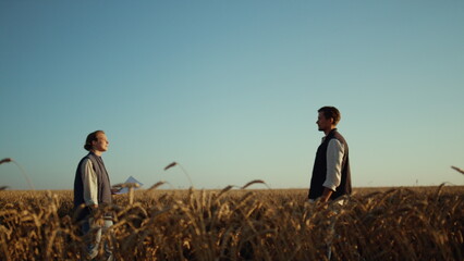 Agricultural business partners concluding successful deal at golden wheat field.