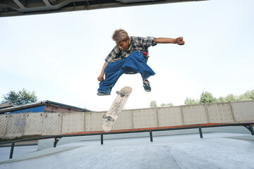 Portrait of teenage boy doing skateboard tricks in air at outdoor skatepark in urban area