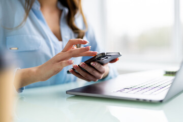 Attractive business woman sits at table in front of laptop and talks on mobile phone, negotiates on the phone.