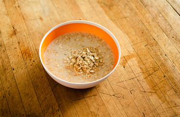 Avena remojada en leche de almendras dentro de un tazón, encima de una mesa de madera desgastada