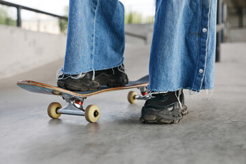 Closeup of teenager riding skateboard outdoors while wearing chunky shoes, copy space