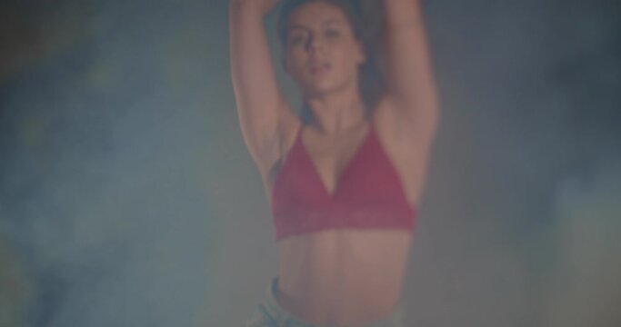 Beautiful girl dancing in bra and jeans, selective focus, smokey scene
