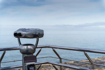 A selective focus shot of binoculars on a seaside