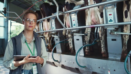 Serious woman dairy farm worker pose in parlour. Agriculture specialist at work.
