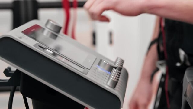 A man in ems suit turns on the stimulation and walks to the exercise equipment