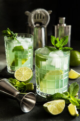 Glass of   beverage with lime, mint, summer cold drink on dark background