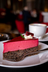 Piece of famous Poppy seed cake with raspberry mousse of Austrian origin served with whipped cream and cup of coffee