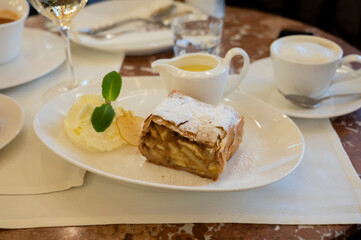 Austrian sweet dessert, portion of apple strudel with whippen cream and hot vanilla sauce served in old bakery cafe in Vienna, Austria