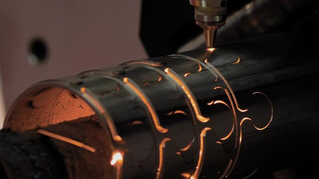 Automatic cnc laser cutting machine working with cylindrical metal workpiece with many sparks at factory, plant - close up, slow motion. Metalworking, industrial, manufacturing and equipment concept