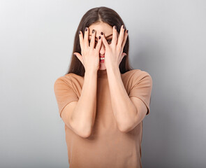 Happy excited fun beautiful woman covering the face the hands on blue grey background. Closeup