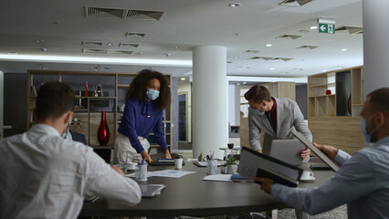 Diverse corporate team meeting wearing face mask in office table. Covid concept.