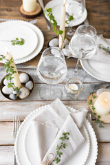 Rustic zero waste wedding decor with natural elements. Wooden table, candles, linen napkins, branches with green leaves. Eco-friendly decoration for the special dinner. Romantic and cozy place