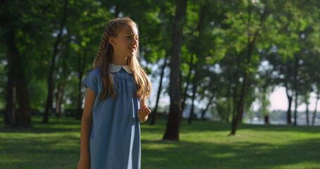 Joyful pretty girl standing on field looking at finger cut left by shuttlecock.