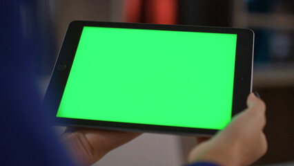 African american woman holding tablet digital device green screen in home office