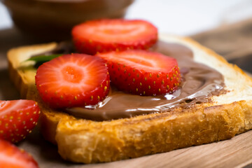 Toasted bread with chocolate spread strawberries on a wooden background