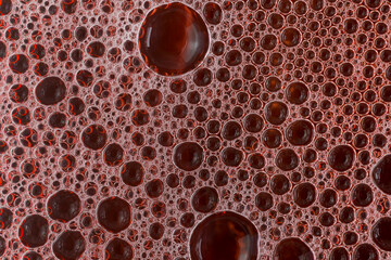 Macro shot of bubbles and soap foam with red liquid, top view, flat background. Texture and...