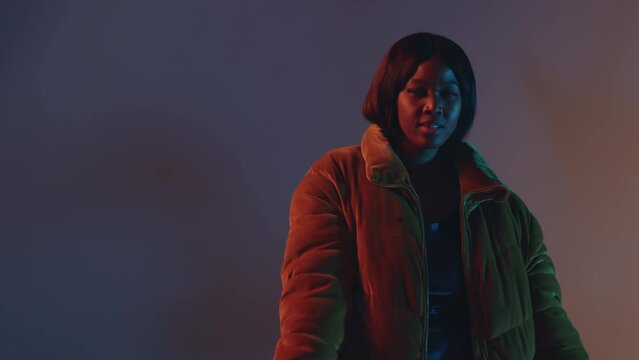 Dancing young african american girl rapper performing dance at hip hop music in colourful neon studio lighting. ProRes