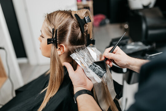 Female stylist putting coloring foils on woman hair in modern beauty salon  Stock Photo