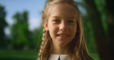 Blonde girl posing alone with pigtail closeup. Gentle kid look camera in park