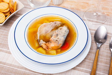 Delicious homemade fish broth with salmon head and vegetables served with crispy salty crackers..