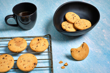 top view of freshly baked cookies, with a trace of coffee and a bowl with three cookies on a blue table.