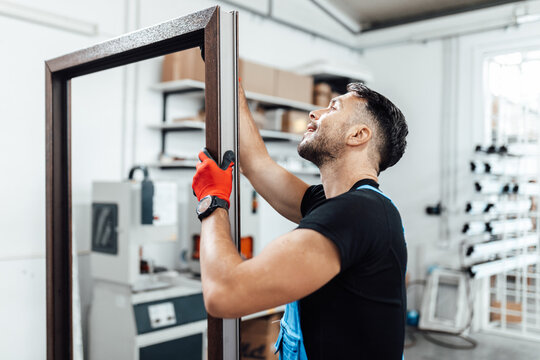 Manual worker works in a carpentry factory, he is assembling PVC windows and doors. Aluminum and PVC windows and doors production.