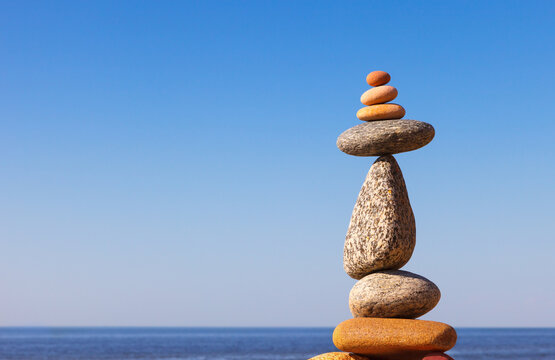 Rock zen Pyramid of balanced stones against the background of the sea and blue sky.