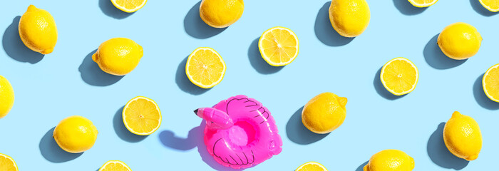 Summer concept with a pink flamingo float and lemons - flat lay