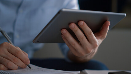 Business man researching tablet analyze corporate data writing notes in office.