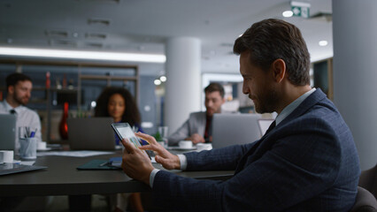 Happy businessman looking tablet searching net with multiracial team in office.