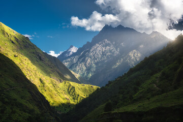 High Himalayan mountains, green forest, blue sky with clouds and sunlight at sunrise in summer in Nepal. Colorful landscape. Mountain valley at sunny day. Travel and trekking in Himalayas. Nature