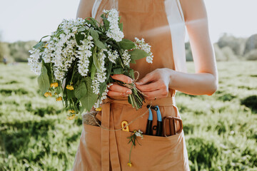 Portrait of beautiful woman making wreath of flowers dandelions on flowering field. Summer...