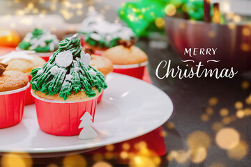 Christmas tree shaped cupcakes with snow sprinkles on christmas lights and festive background. Cooking Christmas treatment for family.