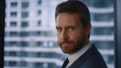 Confident corporate man posing turning head looking camera in company office.